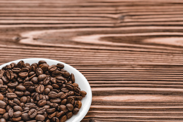 full white plate of coffee beans on brown wooden background