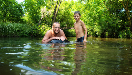 Dad and son play in the river in the hot summer. 