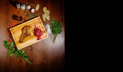 A juicy piece of fried meat lies on a cutting board against a wooden table.Top view