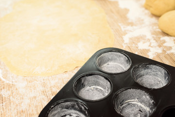 rolled dough with butter on the table with a rolling pin for rolls and rolls. next to it is a cupcake mold . the view from the top, place for text