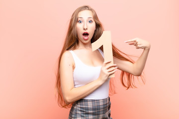 yound blonde woman surprised, shocked, amazed, holding a number 1.