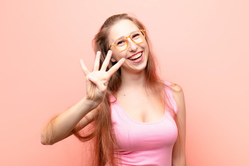 yound blonde woman smiling and looking friendly, showing number four or fourth with hand forward,...