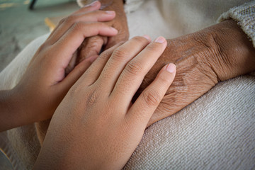 Fototapeta na wymiar Hands of two people represent family warmth and care for the elderly.