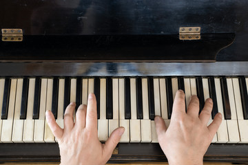 Hands playing the old piano