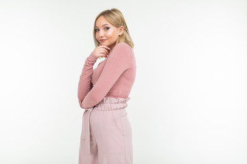 stylish young lady in a pink blouse and pants smiling on a white studio background