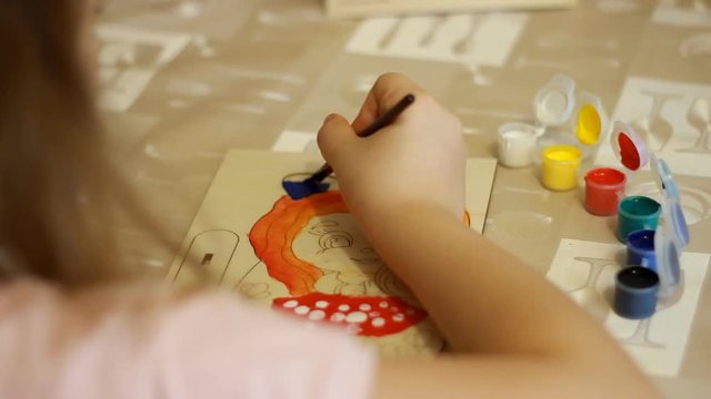 Little girl draws a picture using a paint brush. Child painting art