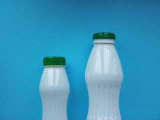 Two white bottle with green bottle cap on a blue background. Front view