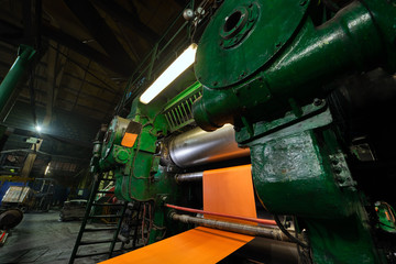 Wide orange polyamide canvas in a conveyor belt making machine.