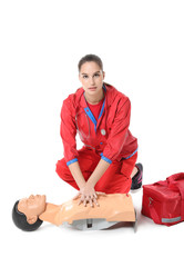 Paramedic demonstrating CPR on mannequin against white background