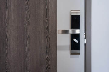 Modern entrance wooden door with metal doorknob handle and security electronic digital door keycard...