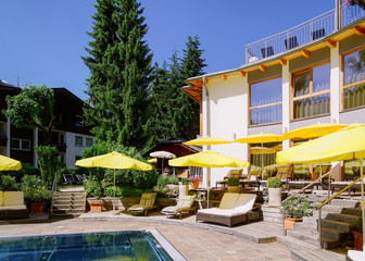 Modern hotel swimming pool and yellow umbrellas at green background