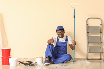 Portrait of African-American painter showing thumb-up in room