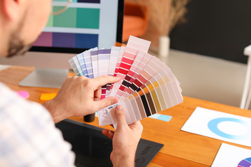 Male designer with color palettes in office