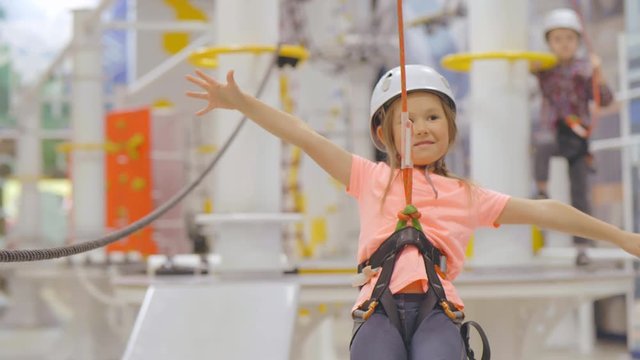 Little girl passing zip line in indoor climbing adventure park