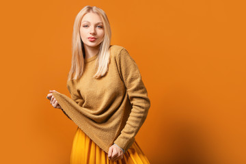 Young woman in warm sweater on color background