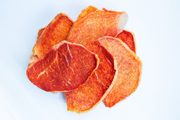 Dried slices of pork, beef with spices on a white background. Crispy meat chips. Tasty appetizer. View from above.