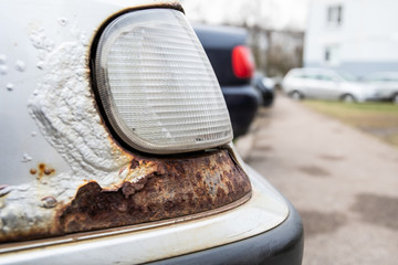 Paint bubbles, cracked paint and rust. White car headlamp