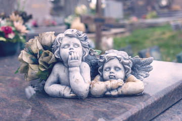 two angels in a cemetery above a grave, closeup of stone angels