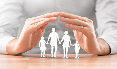 Family care concept. Hands with paper silhouette on table.