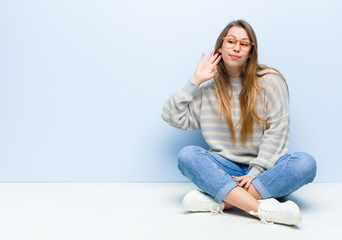 young blonde woman looking serious and curious, listening, trying to hear a secret conversation or...