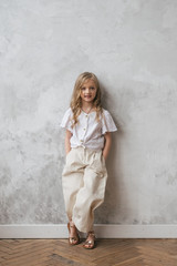 Beautiful charming girl child 7 years old. smiling, looking at the camera. Stylishly fashionably dressed in white trousers and a shirt.