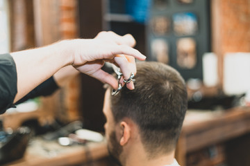 Haircut at the hairdresser. Barber cuts the hair on the client's head. The process of creating hairstyles for men. A man in a barbershop. The near plan. Equipment stylist. Selective focus