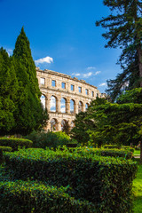 Croatia, Istria, fragment of ancient Roman Arena in city of Pula, landscape view through the trees in park