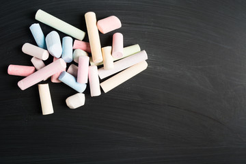 Stack of colorful pastel pieces of chalk over blackboard for school concept