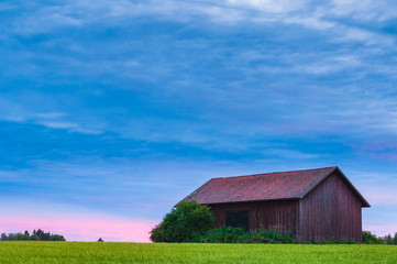 Fototapeta na wymiar Wooden barn on green field