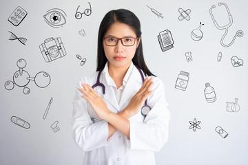 Doctor with forbidding gesture with hand drawn medical sketches. Young Asian female doctor wearing...