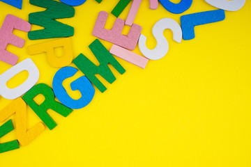 ABC wooden letters alphabet scattered on a yellow background. Education and copy space