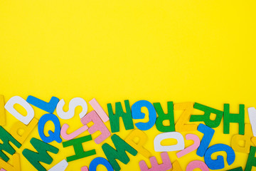 ABC wooden letters alphabet scattered on a yellow background. Education and copy space