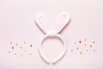 Obraz na płótnie Canvas Funny cute bunny eggs and bunny rabbit ears for kids on pastel pink table top, Easter holiday concept. Easter decoration for kids flat lay, copy space