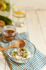 Wooden spoon with flax seeds over soy yogurt with seeds and fruit slices, blurred