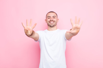 young handsome man smiling and looking friendly, showing number nine or ninth with hand forward,...