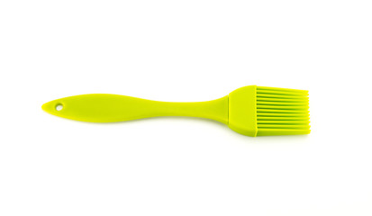 The kitchen brush is silicone, light green in color. Plastic accessories for the kitchen, cooking and coating. White isolated background.