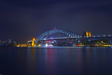 Sydney Harbour Bridge illuminating the harbour and circular quay with vibrant colourful lights at midnight in NSW Australia