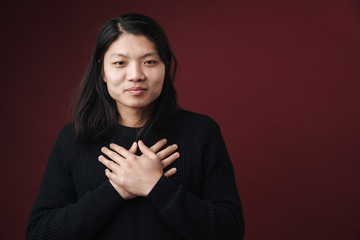 Image of happy asian man posing on camera with hands on his chest