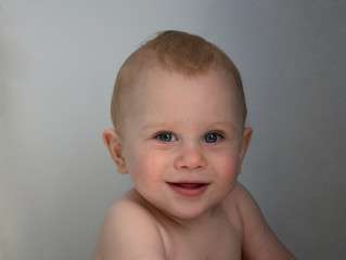 Close up photo of smiling cute little baby boy on grey background