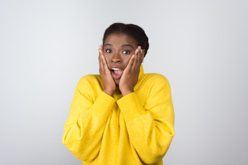 Shocked young woman looking at camera. Portrait of scared young African American woman holding...