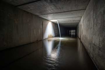 Waterfall in underground sewer square tunnel.