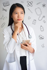 Pensive intern using phone with hand drawn medical sketches. Young doctor facing with problems and...