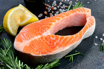 salmon steak on a dark background with lemon and spices