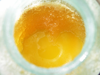 Flower candied and liquid honey in a glass jar close-up, top view