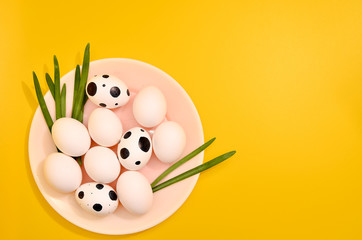Many White eggs on a plate with green myrtle leaves pattern on yellow color background. Spring and Easter holiday concept with copy space.