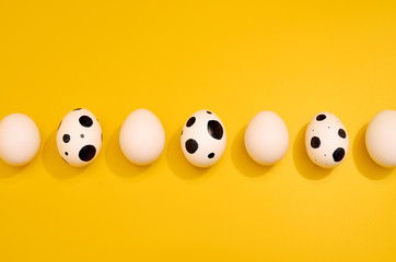 Many White eggs with green myrtle leaves pattern on yellow color background. Spring and Easter...