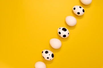 Naklejka premium Many White eggs with green myrtle leaves pattern on yellow color background. Spring and Easter holiday concept with copy space.