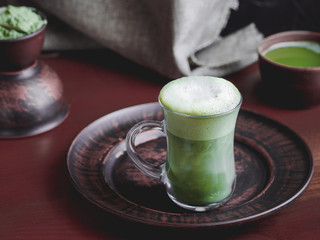 matcha latte tea in a glass goblet on a clay dish