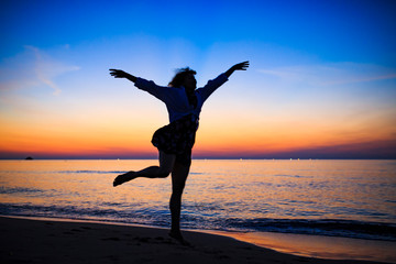 夕暮れの海辺で踊る白人女性
