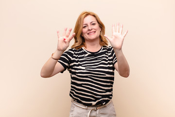 middle age woman smiling and looking friendly, showing number nine or ninth with hand forward,...